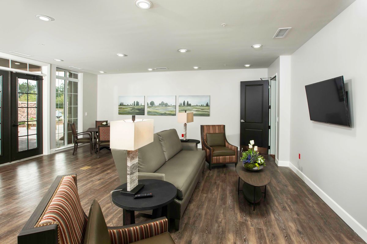 A modern living room with a sofa, coffee table, and decorative lamps on wooden flooring.