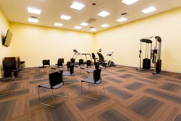 A fitness room with exercise equipment and arranged chairs.
