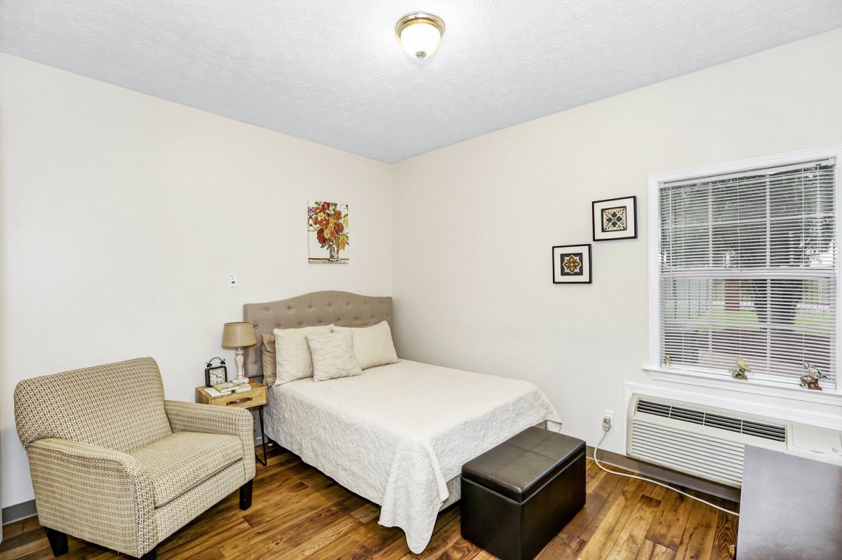 A cozy bedroom with a bed, armchair, and decorative elements.