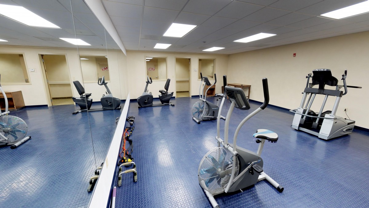 A gym with exercise bikes and mirrors in a workout room.
