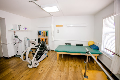 A well-equipped physical therapy rehabilitation room featuring exercise equipment and a treatment table.
