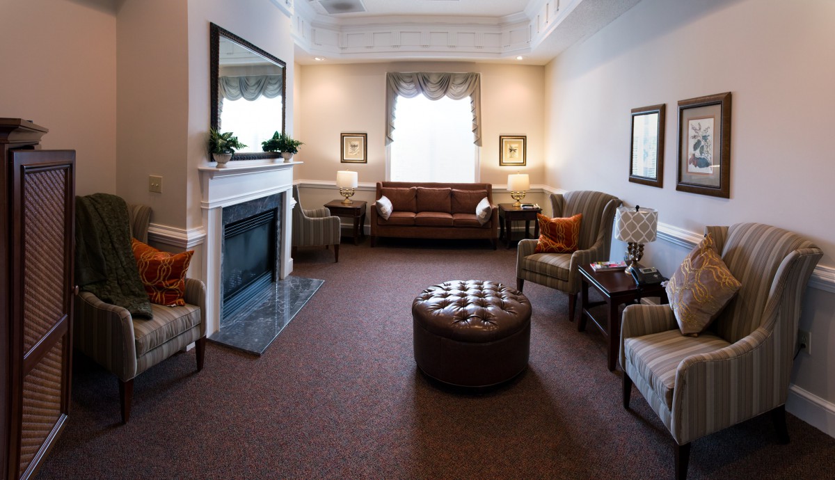 A cozy living room featuring a fireplace, sofa, armchairs, and a central coffee table.
