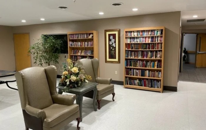 A cozy reading area with bookshelves, comfortable chairs, and a decorative table.
