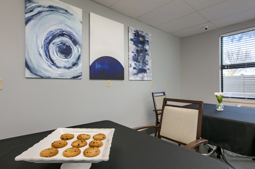 A cozy breakroom featuring a plate of cookies, modern furniture, and abstract artwork on the walls.