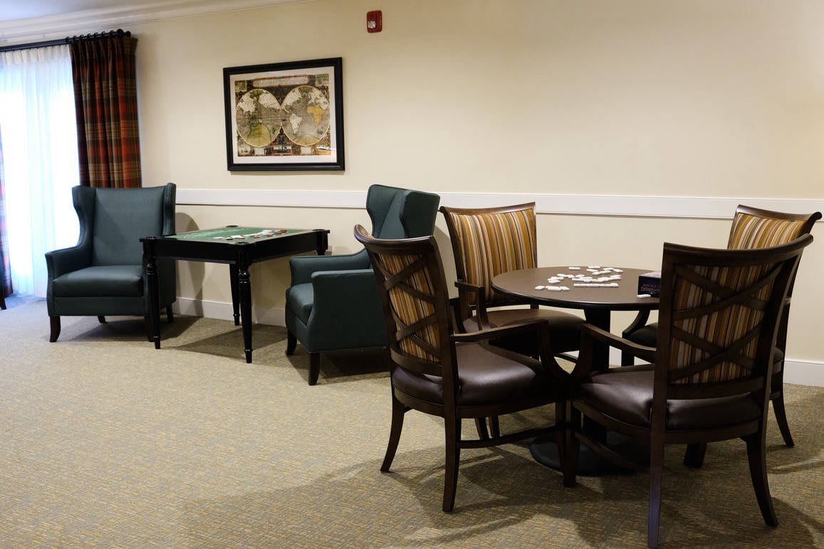 A cozy lounge area with tables, chairs, and wall art.