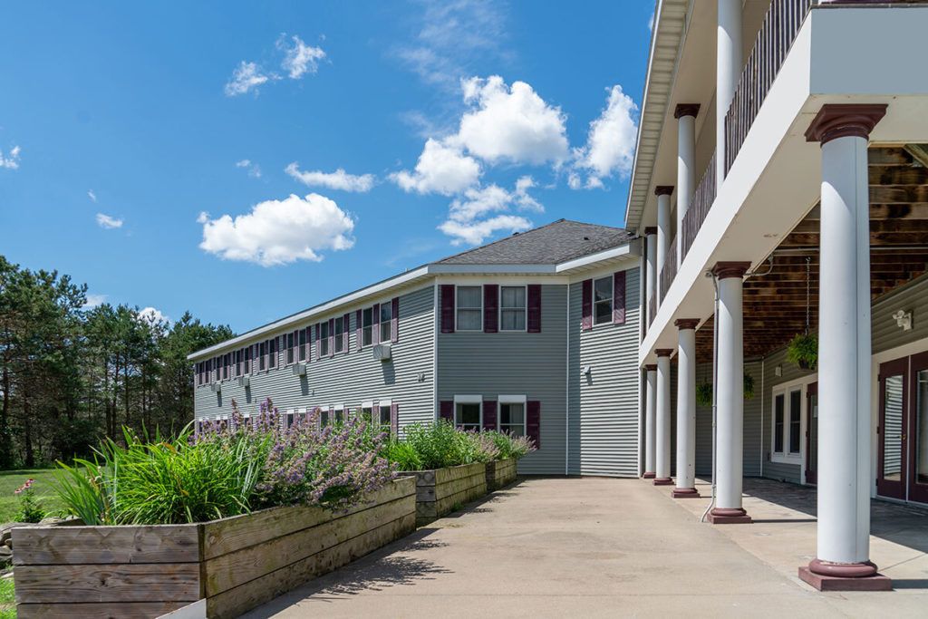 A modern building with columns and landscaped surroundings under a clear blue sky.