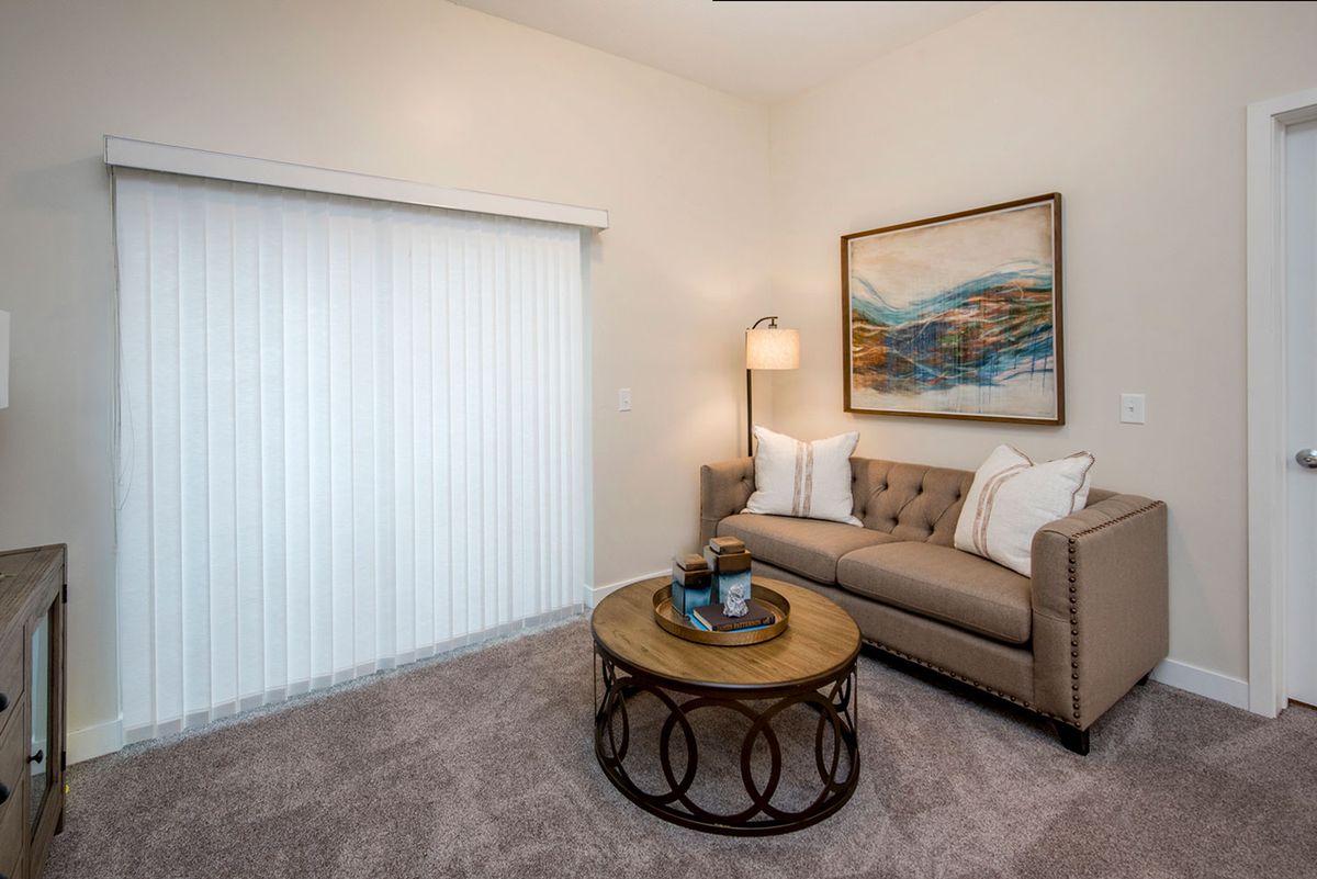 A cozy living room featuring a comfortable sofa, coffee table, standing lamp, and abstract artwork on the wall.