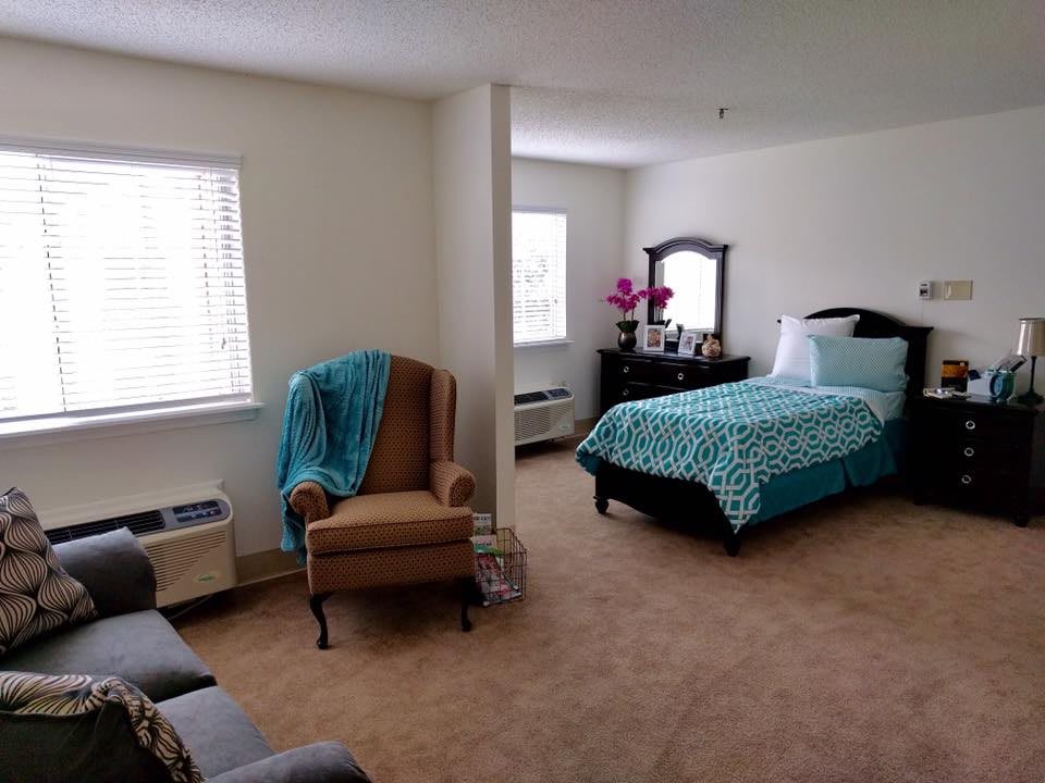 A cozy bedroom with a single bed, armchair, and dresser.
