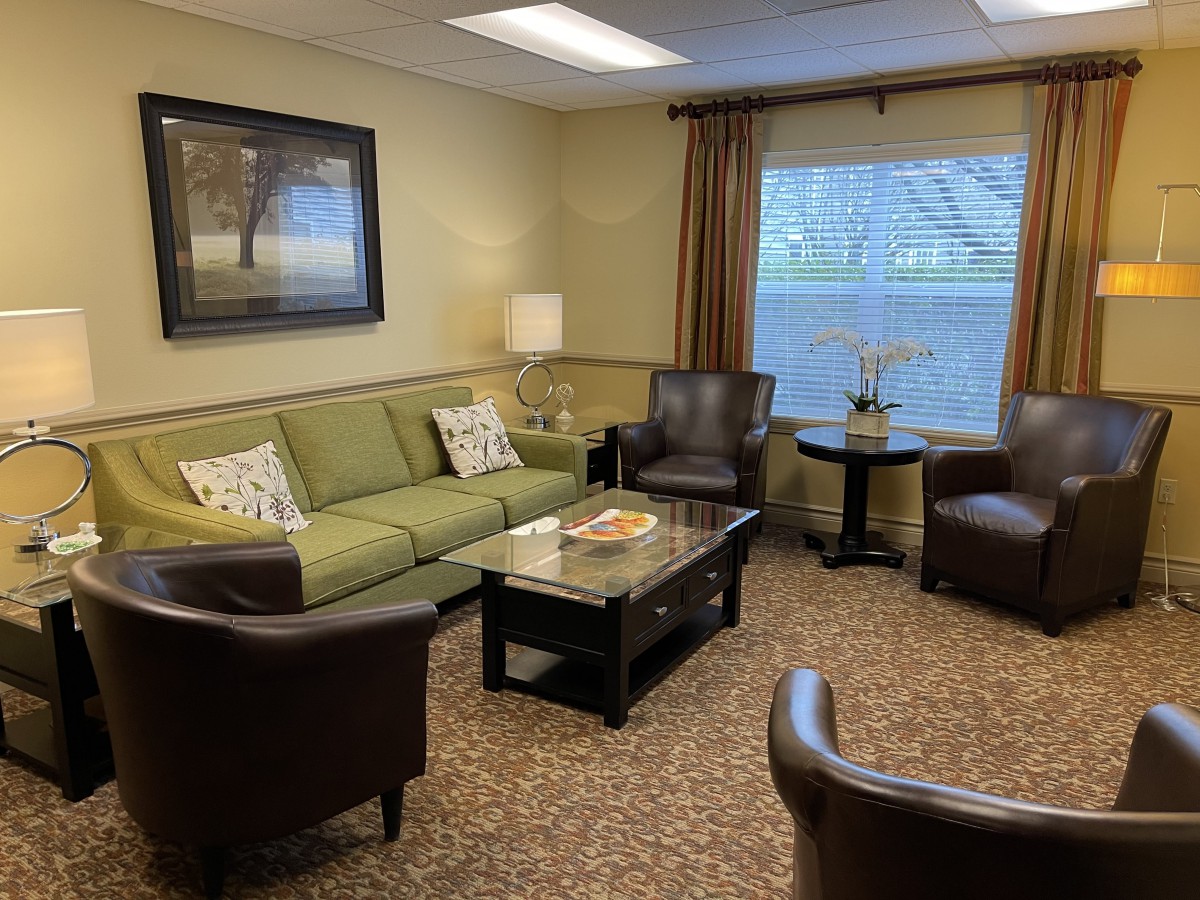 A cozy living room with a green sofa, leather chairs, and a coffee table.