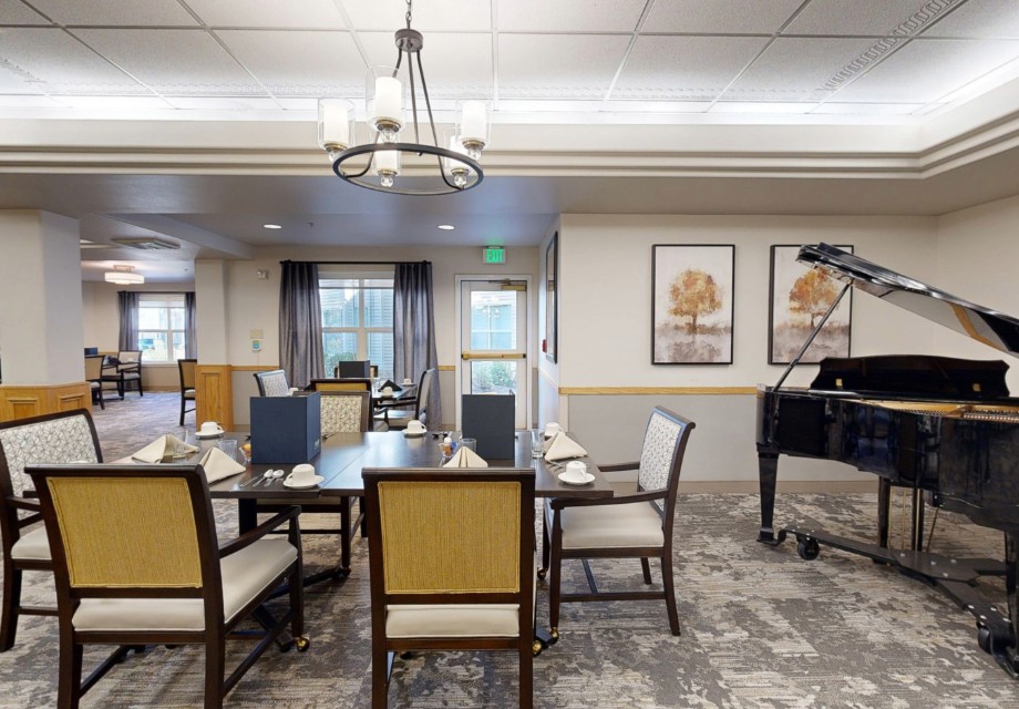 A well-appointed dining room with elegant furniture, a piano, and framed artwork on the walls.