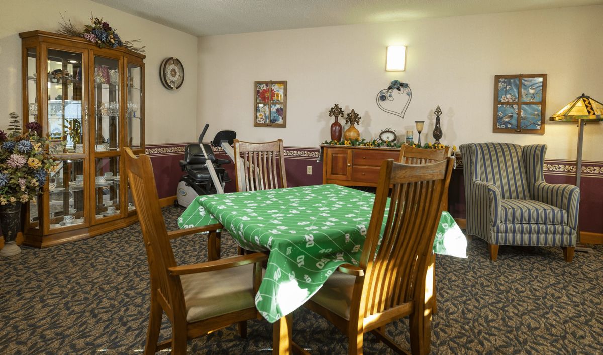 A cozy dining room with a wooden table and chairs, featuring a green tablecloth.