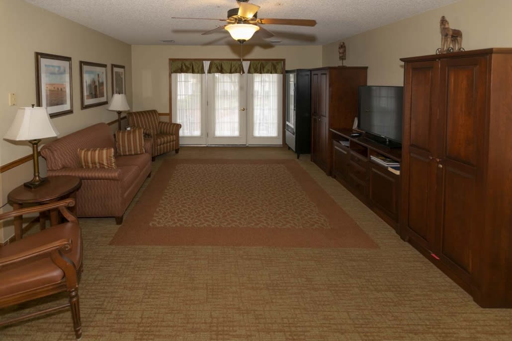 A spacious living room with a sofa, TV, and wooden cabinetry.