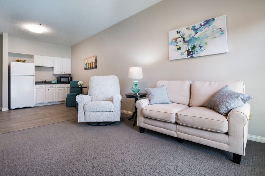 A cozy living room with a sofa, armchair, and adjacent kitchen area.