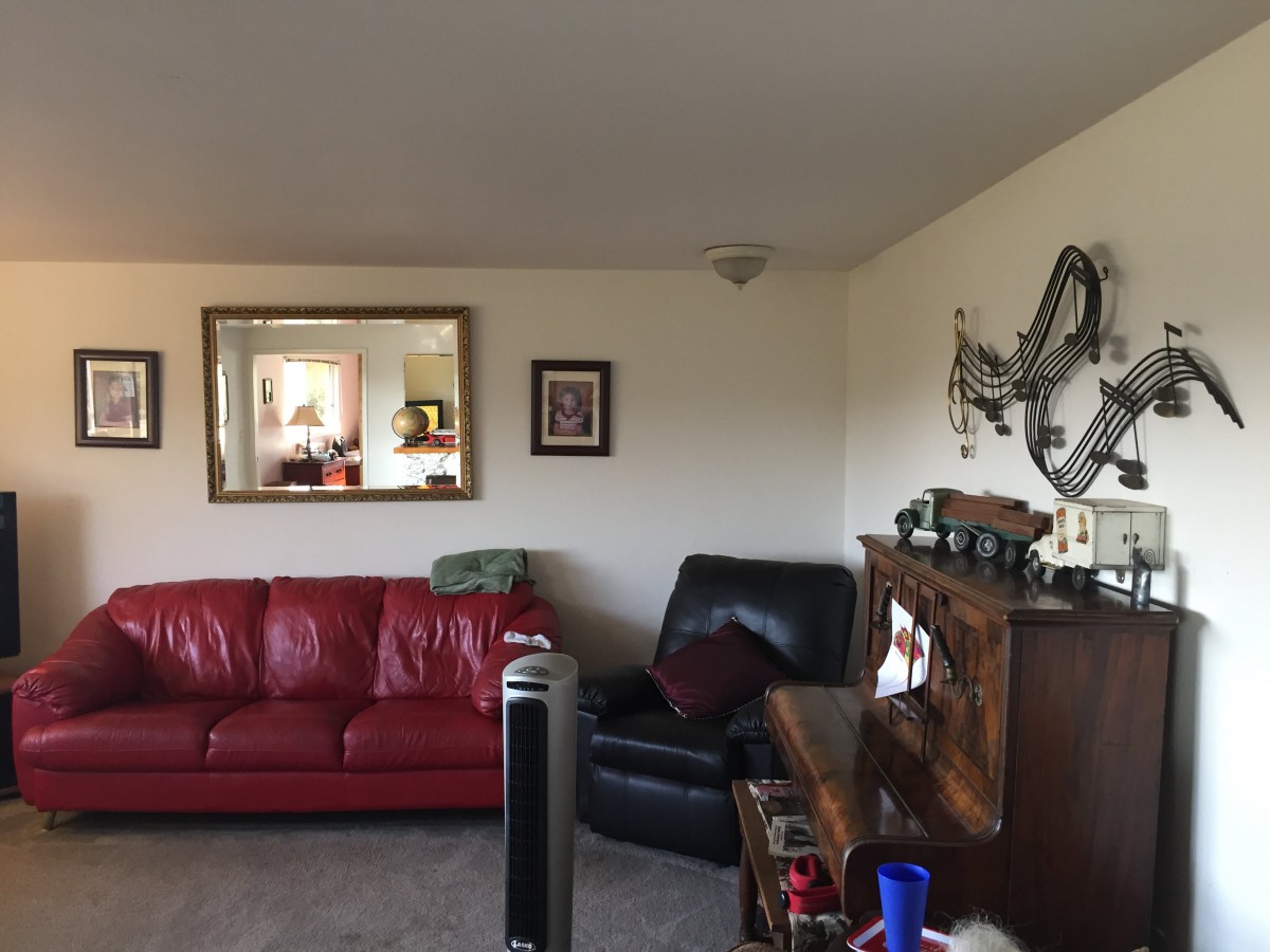 A cozy living room featuring a red sofa, a mirror on the wall, and wooden furniture.
