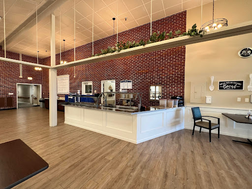 A modern cafe interior featuring a brick wall and wooden flooring, with bright lighting creating an inviting atmosphere.
