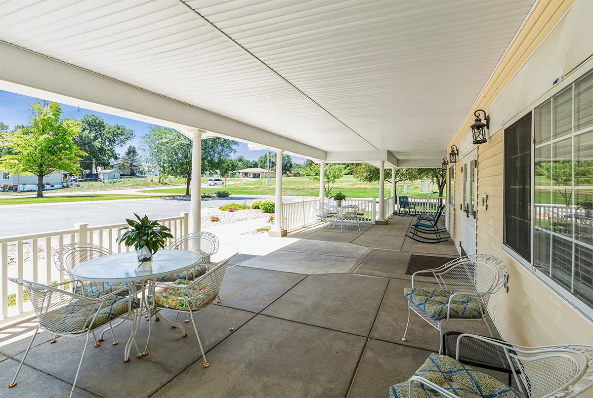 A spacious covered porch with outdoor seating and garden views.