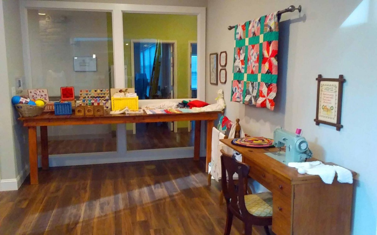 A cozy sewing room featuring a colorful quilt and a wooden workspace.