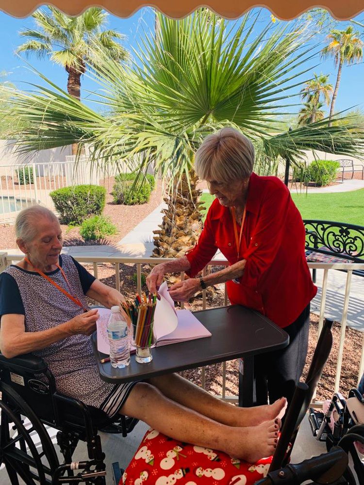 Two elderly individuals enjoying a sunny outdoor setting, one providing assistance to the other.