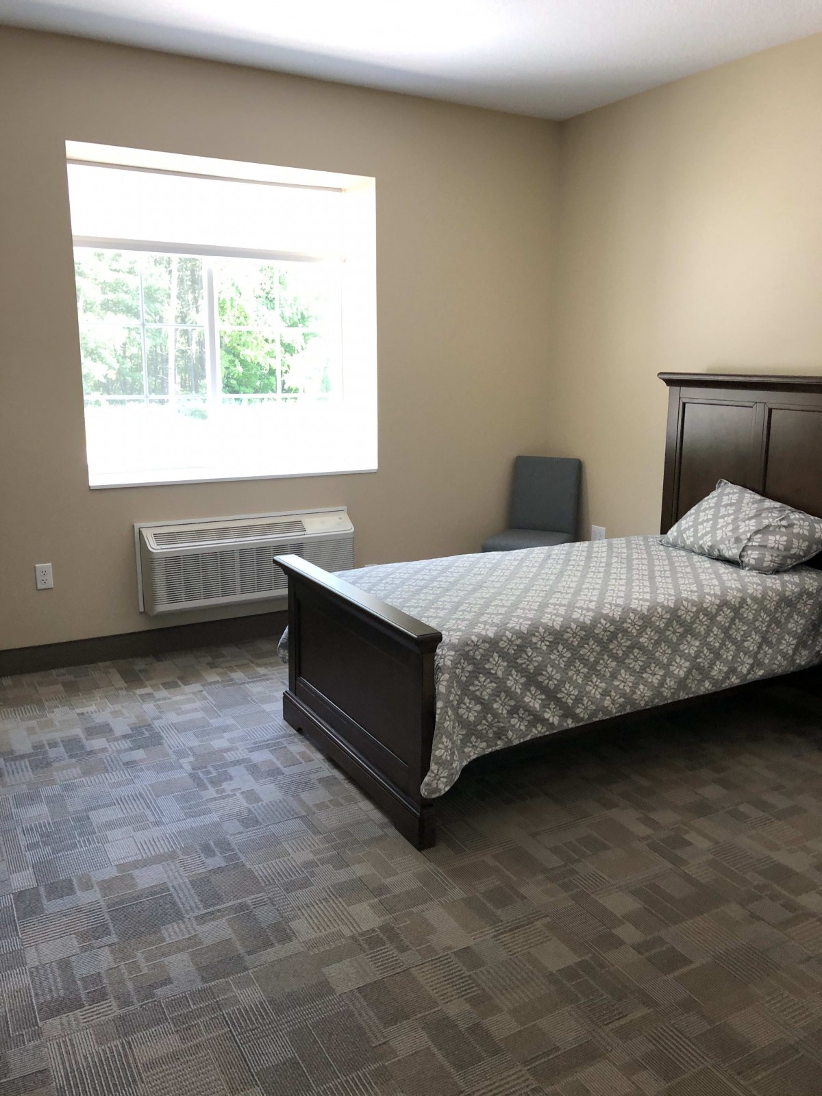 A minimalist bedroom with a single bed, chair, and window.