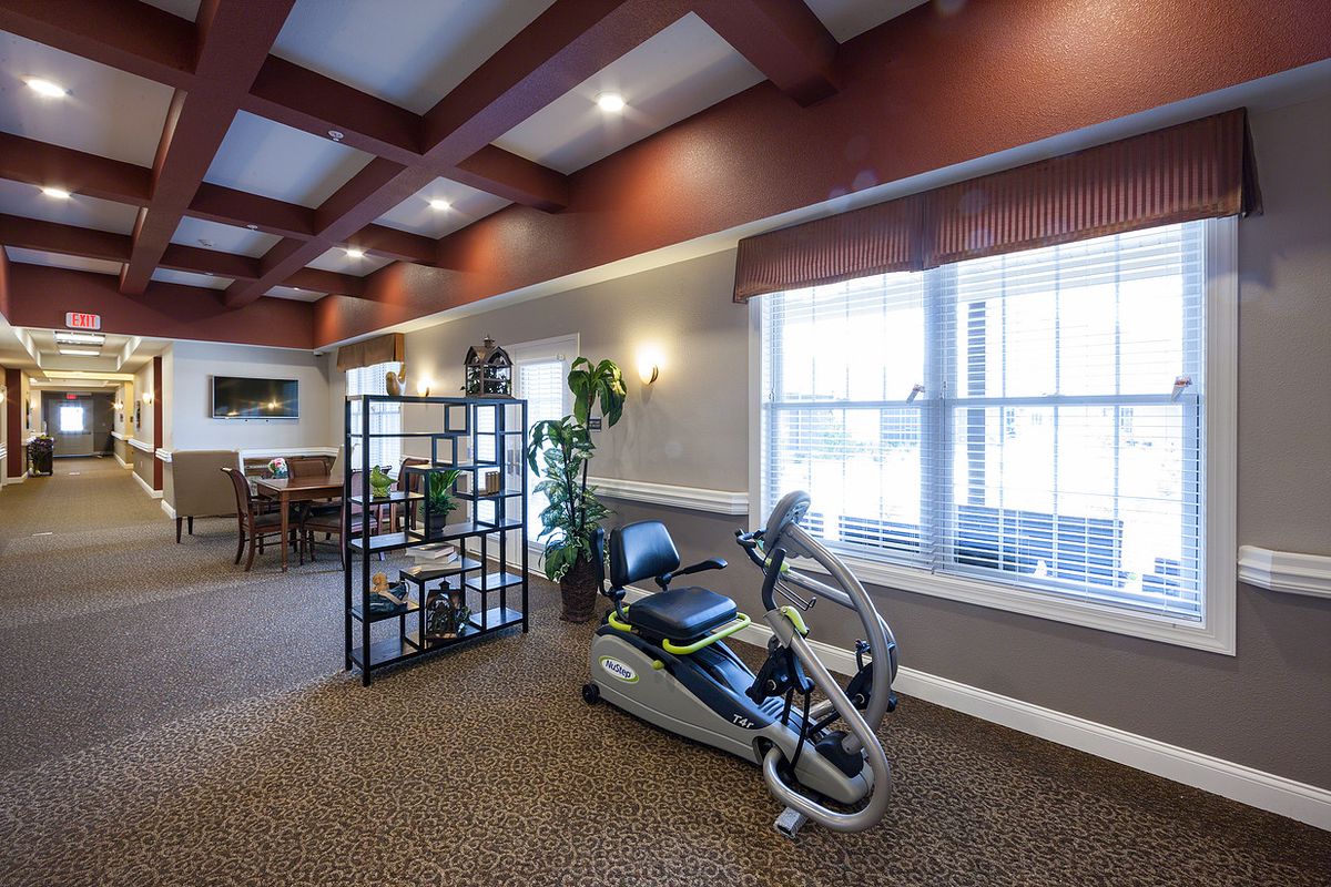 A well-lit indoor space featuring an exercise bike and comfortable seating.