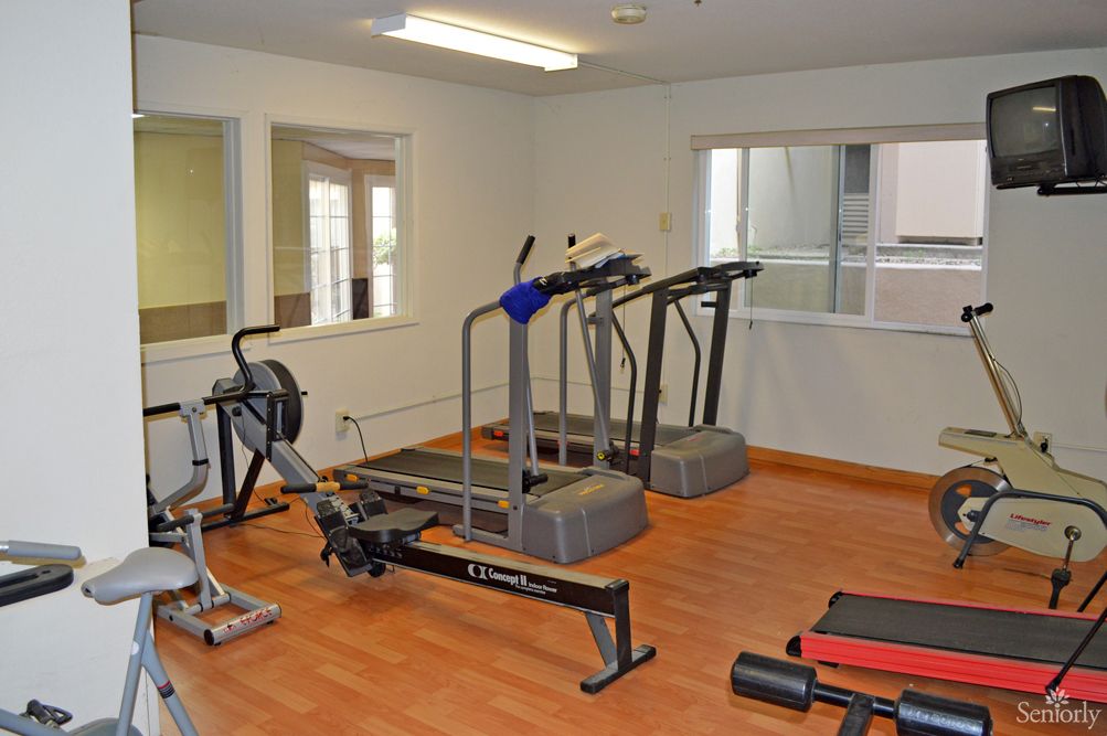 A small gym with exercise equipment including treadmills and a rowing machine.
