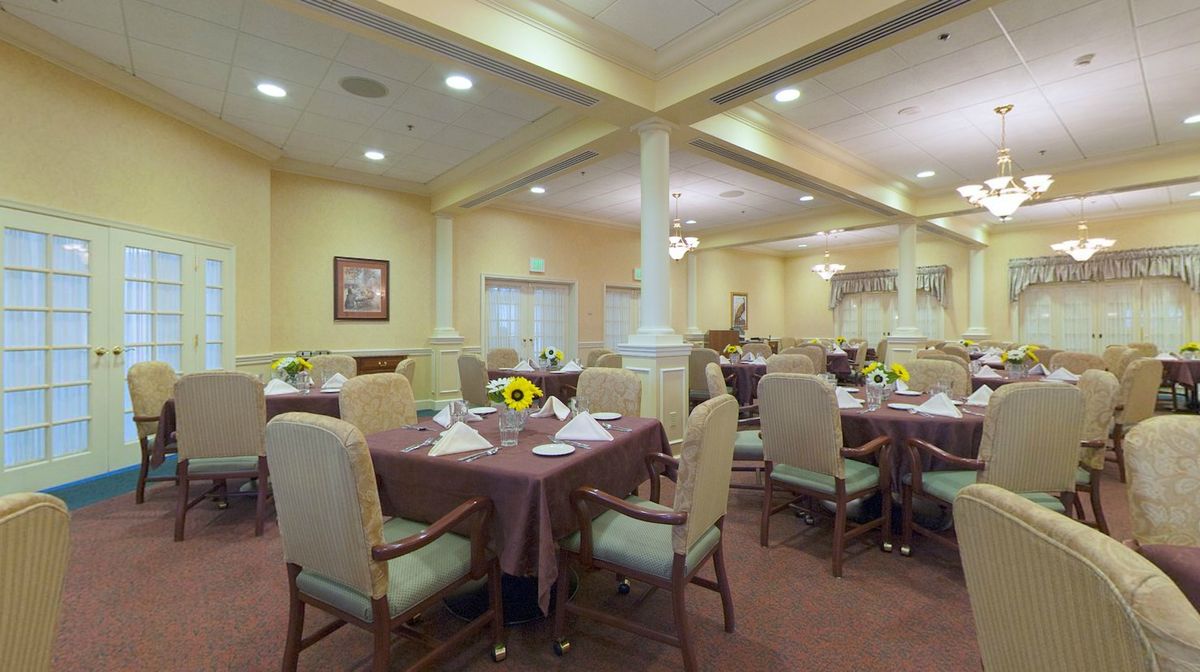 An elegantly decorated dining room with neatly arranged tables and sunflower centerpieces.