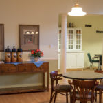 A cozy dining area with a round table and chairs, adorned with warm lighting and decorative elements.