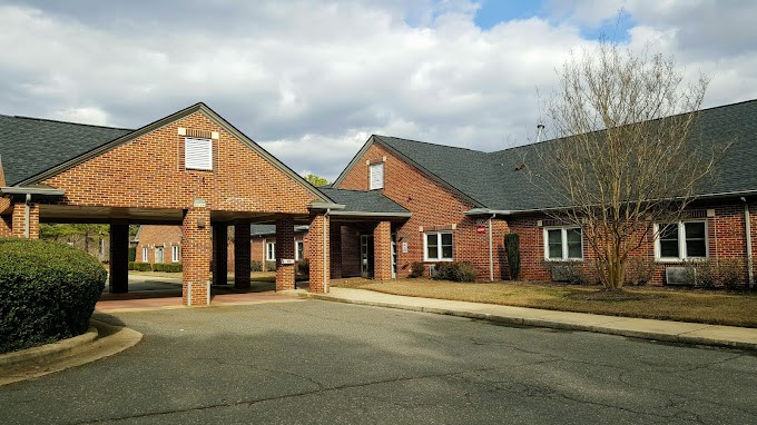 A brick building with an entrance driveway under a partly cloudy sky.