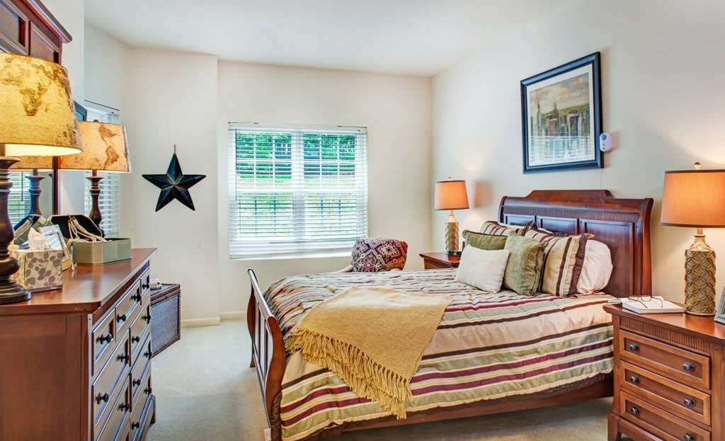 A cozy bedroom featuring a neatly made bed with striped bedding, a bedside lamp, and decorative elements like a star on the wall and a framed picture.