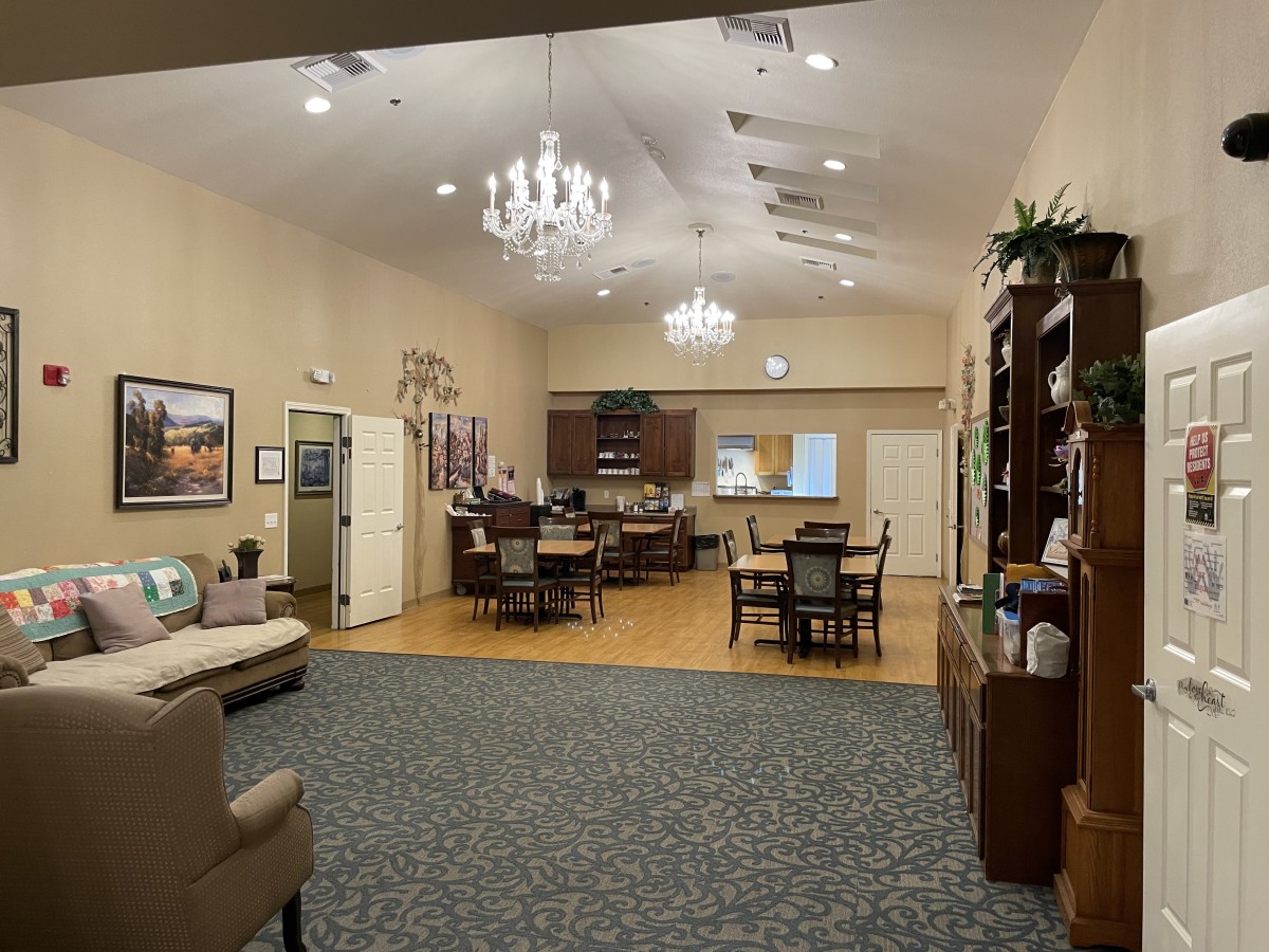 A spacious lounge area with elegant chandeliers, comfortable seating, and various tables arranged for relaxation and socializing.