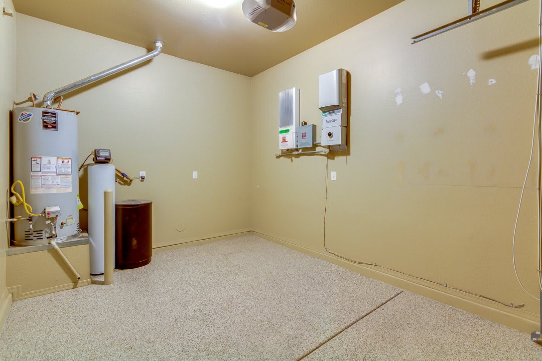 An empty utility room with water heaters and beige walls.