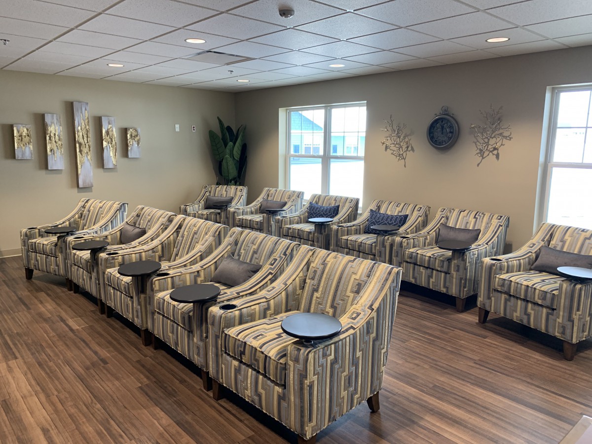 A modern lounge area with striped chairs arranged in a row, featuring small round tables and contemporary wall art.