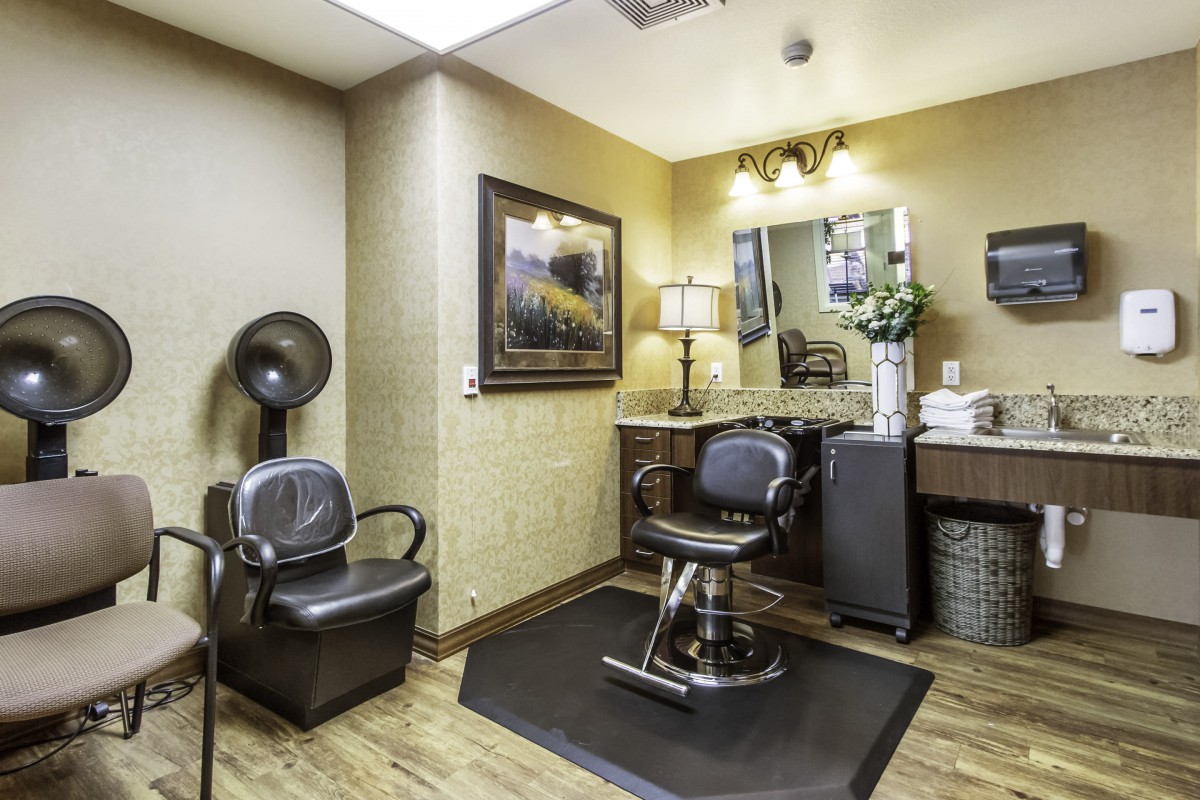 A well-equipped hair salon room with a barber chair, mirror, and various salon equipment.