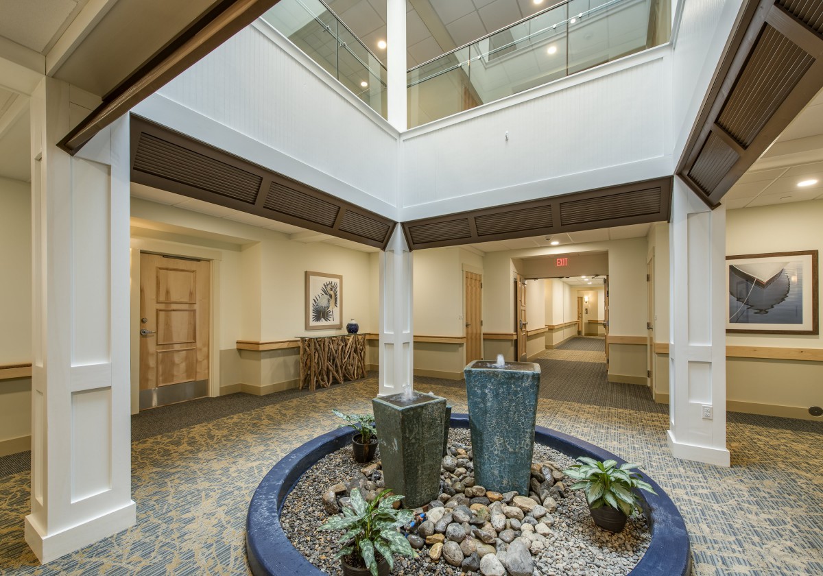 A modern lobby with a central fountain and surrounding plants.