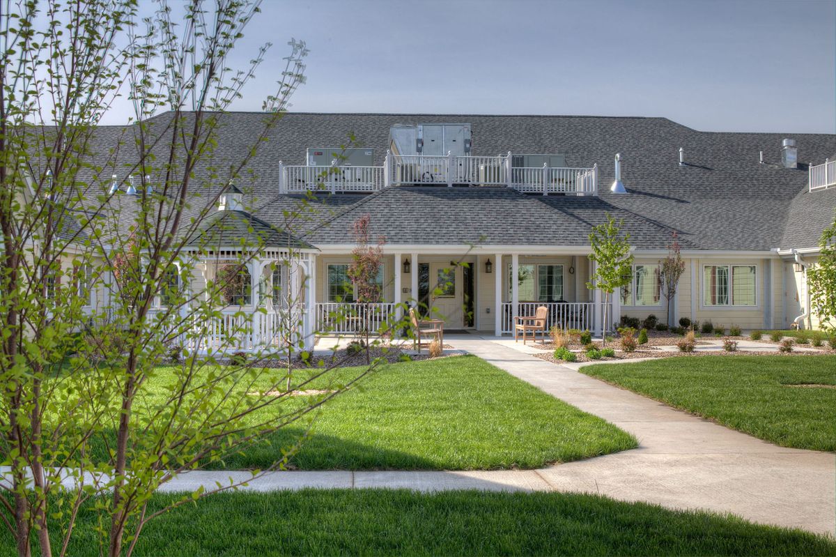 A beautiful residential house with a well-maintained lawn and a spacious front porch.