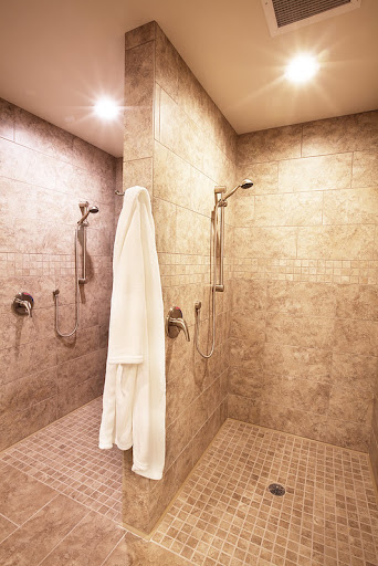 A spacious and modern shower area featuring elegant tile work and a neatly hung white towel.