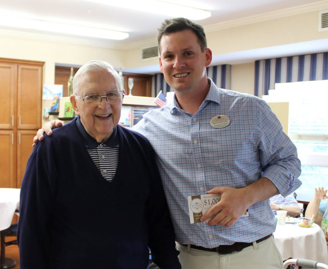Two people standing together in a room, smiling.