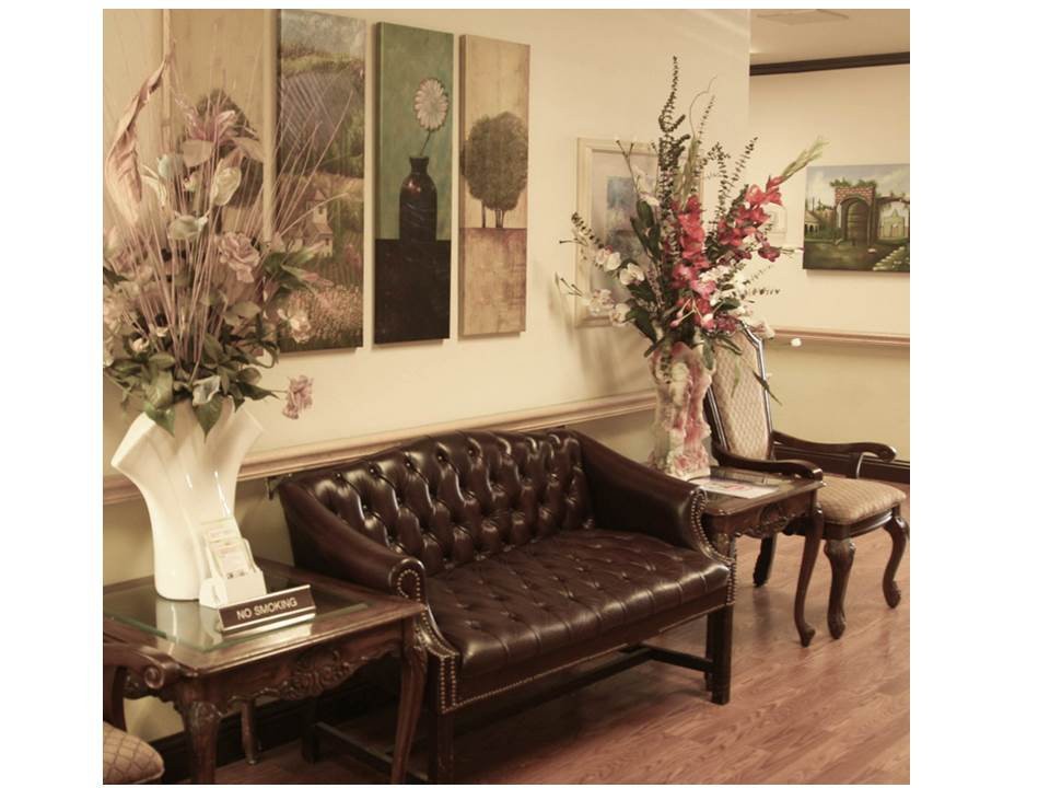 A cozy waiting room with a leather sofa, elegant flower arrangements, and artwork on the walls.