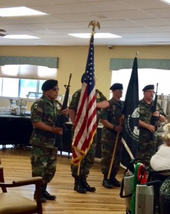 A military honor guard presenting the American flag during an indoor ceremony.
