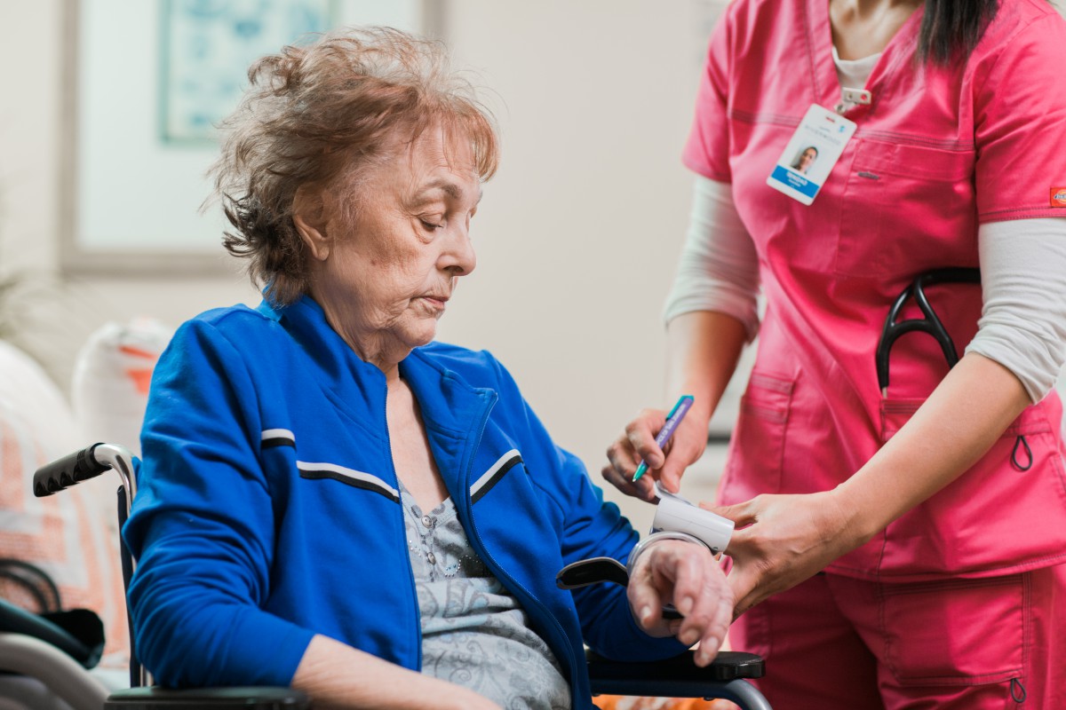 A nurse assists an elderly woman during a medical check-up.