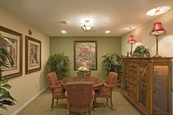 A cozy interior living space with a round dining table surrounded by chairs, adorned with artwork and decorative plants.