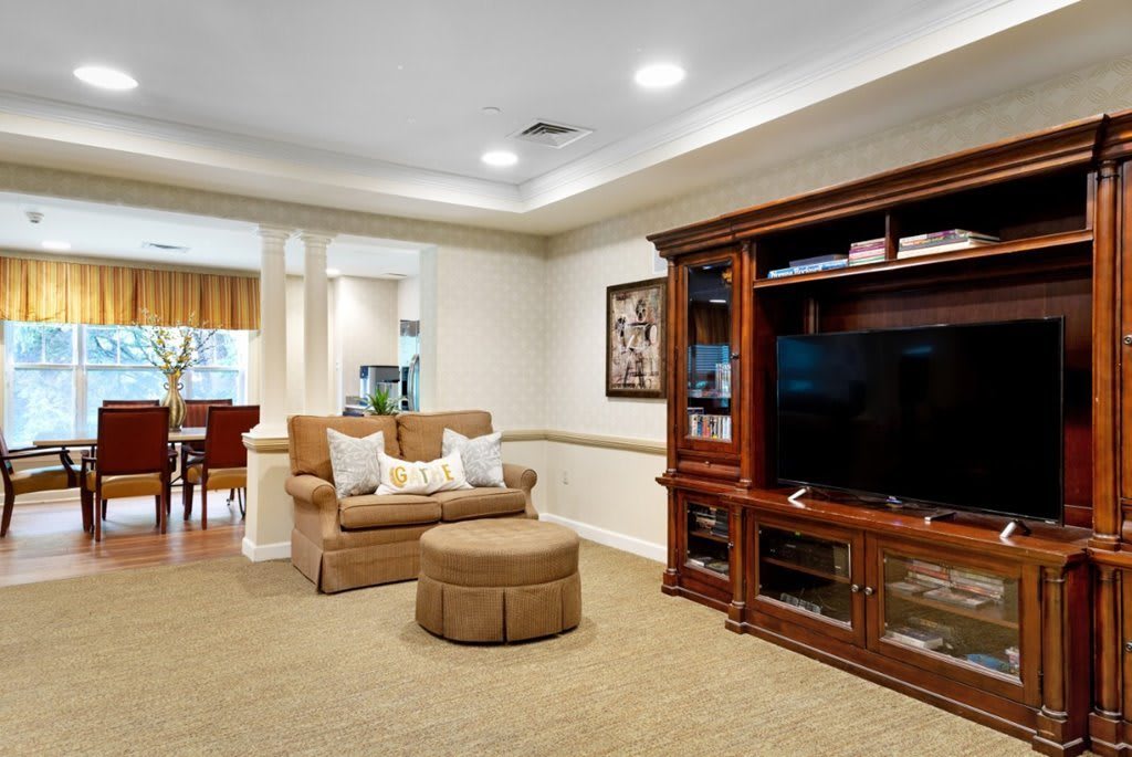 A cozy living room featuring a comfortable sofa, ottoman, and an entertainment center with a large television.