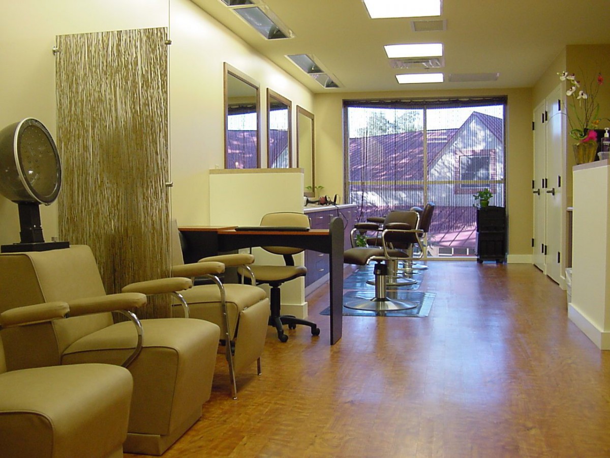A modern hair salon interior with comfortable seating and large mirrors.