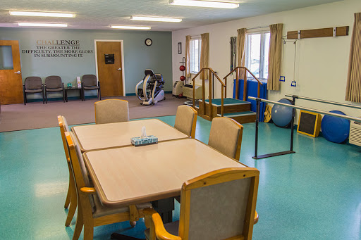A spacious rehabilitation and therapy room featuring a dining area and various physical therapy equipment.