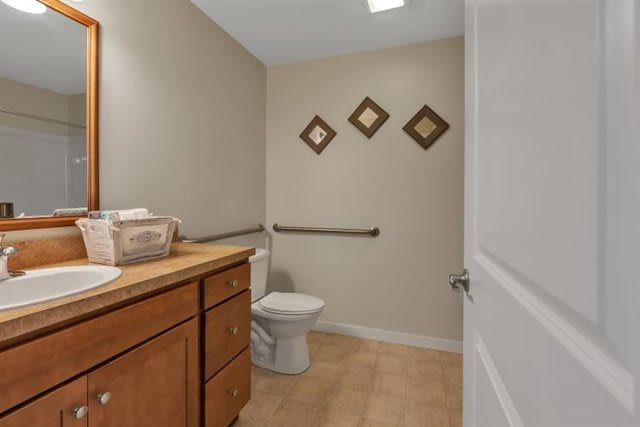 A clean and simple bathroom featuring a wooden cabinet, toilet, and wall decorations.