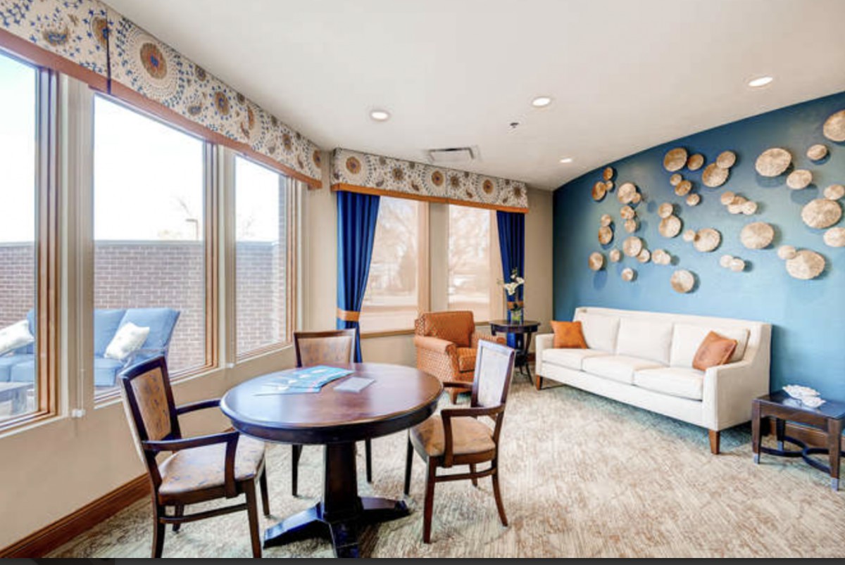 A cozy living room with a round table and chairs, a comfortable sofa, and decorative wall art.