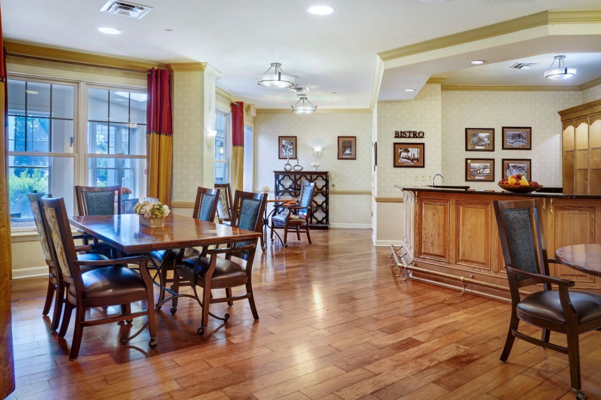 A well-lit dining area with a hardwood floor, featuring a dining table, chairs, and a separate bar section.