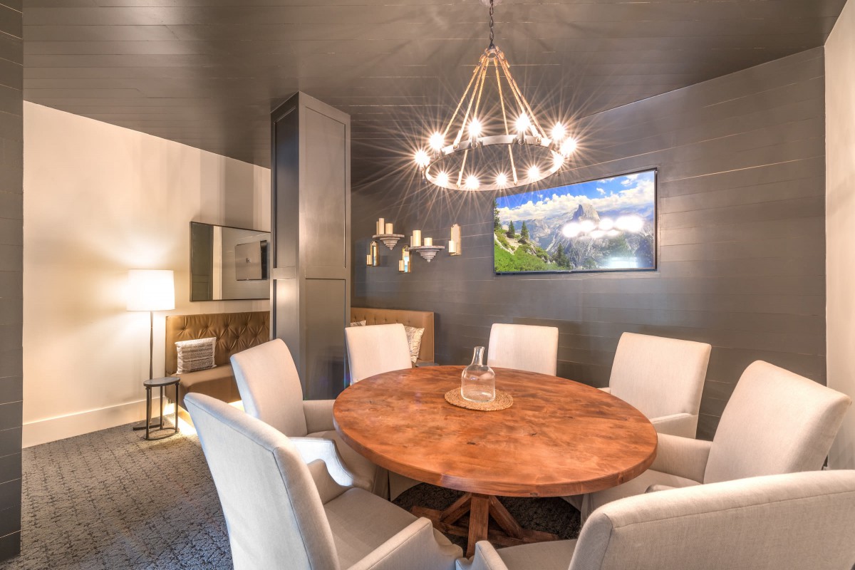 A modern dining room with a round wooden table and elegant chandelier.
