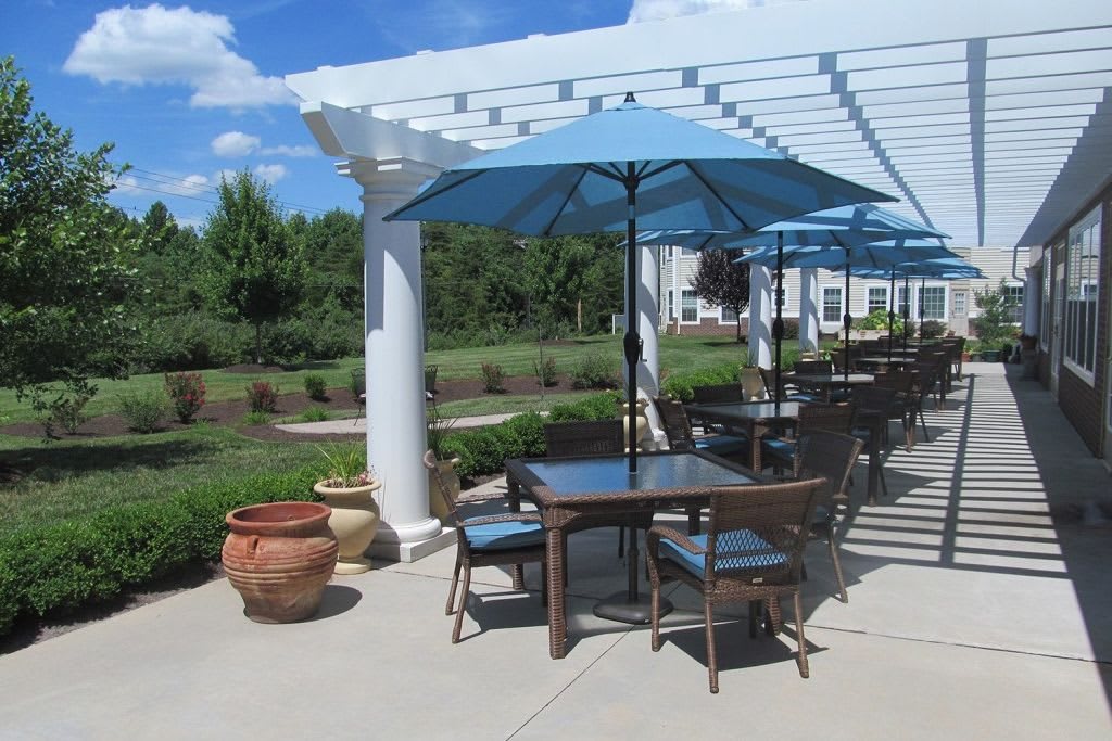 An inviting outdoor patio area with tables and blue umbrellas under a clear sky.