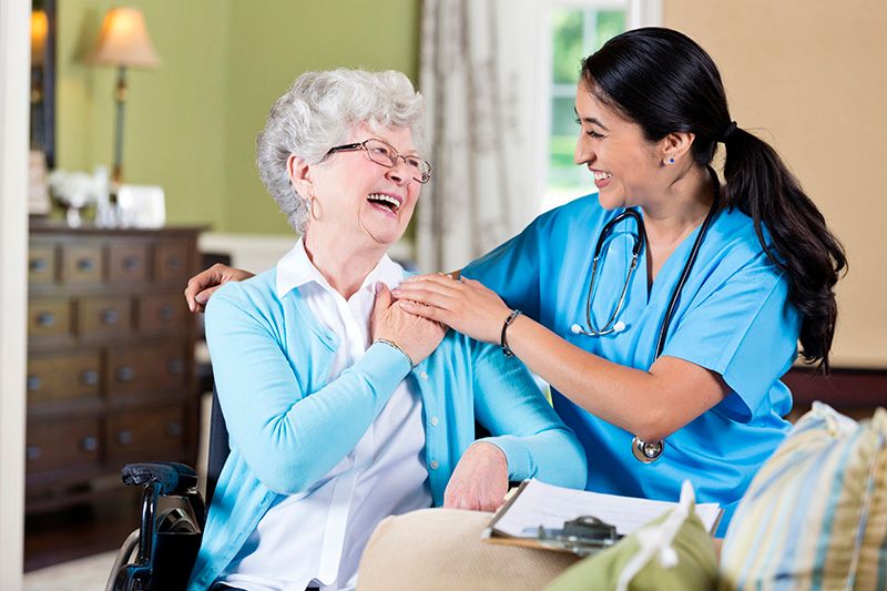 A nurse shares a joyful moment with an elderly woman, promoting companionship in healthcare.